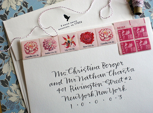 Calligraphy by Primele Beautiful handwritten calligraphy on an envelope that has stamps with flowers across the top of it.