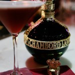 A French martini, the heroine of the night! A photo of a bottle of Chambord with a French martini to the left of it. A fancy Chambord lid sits on a burgundy Chambord napkin.