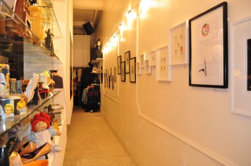 Vintage Garage Photo of a wall on the right side of a narrow corridor with framed artworks.