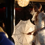 Anna Campbell Model in dreamy white lace outfit, holding a white lace parasol to the side.