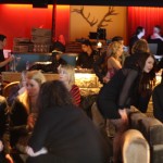Long Room A crowded bar with low grey/ fawn couches with a long bar in the background. Behind the bar is red curtains and a pair of antlers on the wall.