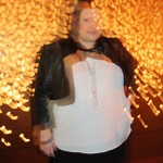 all sparkly like Yours truly posing for a photo in a white top and black pleather jacket. The lighting is blurry and atmospheric due to the lighting feature behind me.