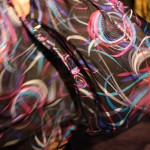master/ slave Detail of model's skirt billowing behind her. The fabric features a large pink, white and cyan circular pattern.