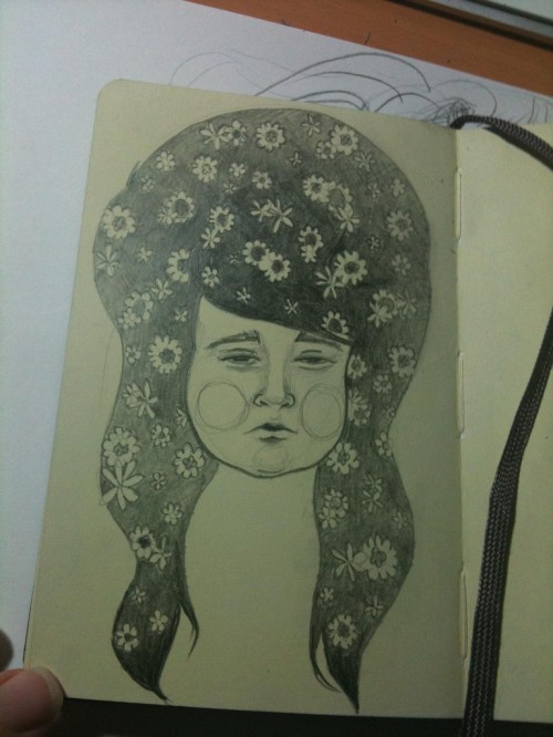 Pencil illustration in a sketchbook of a chubby girl with big hair with flowers in it.