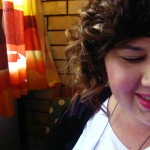 A photo of me with my new haircut, short on the right side and long on the left. In this photo the long bit has been curled. I'm half cut off and you can only see the left side of me.