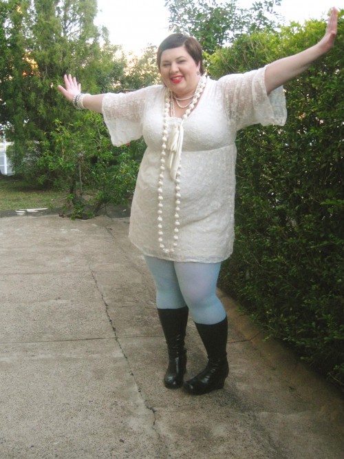 Outfit photo of me wearing a cream lace dress with big sleeves that are elbow length, mint coloured tights, black boots, and lots of cream and pearl necklaces. My arms are stretched out to show off the sleeves.