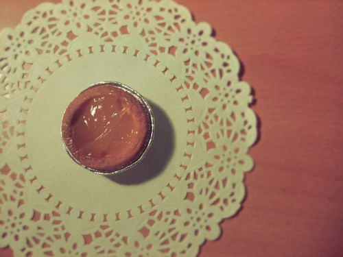 A photo of a very very small pie with a citrus butter type filling sitting on a paper doily shot from directly above.