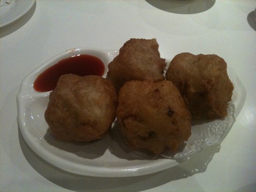 Photo of four huge fried dim sim with some sweet and sour sauce.