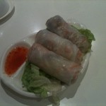 Photo of three rice paper rolls on a bed of green lettuce with some sweet chilli sauce.