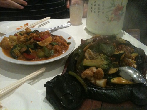 Photo of two large dishes: at rear satay "chicken" and in front some sizzling beef in pepper sauce.