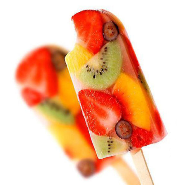 Photo of two ice blocks made up of slices of fruit, like strawberries and kiwi fruit.