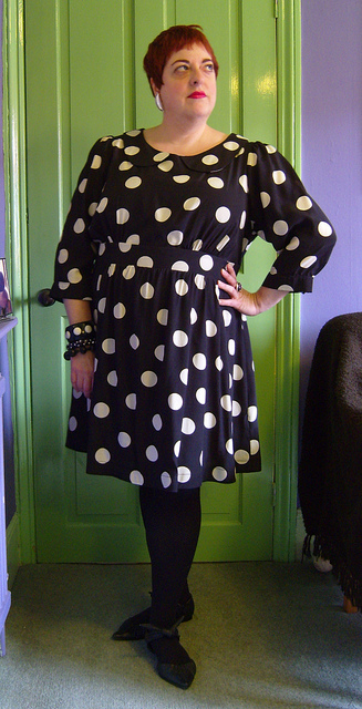 Photo of an older pale skinned woman with short dark hair wearing the polka dot dress.