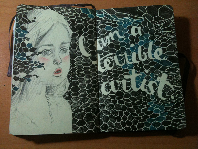 Photo of a drawing across two pages of a moleskine, a pencil sketch of a young girl with rosy cheeks and lips sits agains a black and dark teal fishnet pattern with "I am a terrible artist" written in it.