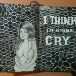 Photo of a drawing across two moleskine pages: a pencil drawing of a young woman with long hair, and an open shirt that just covers her breasts against an undulating fishnet pattern which has the words "I think I'm gonna cry" written in it.