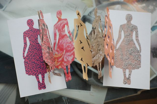 Photo of one of those chain cut outs, with the cut outs being in the shape of a woman holding her skirt out. Each fold is a different print.