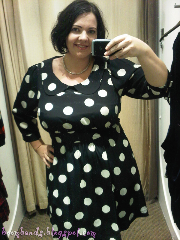 Photo of a chubby pale skinned woman with short dark hair taking a photo in the mirror as she wears the polka dot dress.