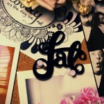 Photo of the laser cut acrylic fat lettering sitting on a pinboard with a bunch of other stuff stuck to it including some photobooth photos of Nick and I, my lovely postcard, some polaroids and some faux flowers.