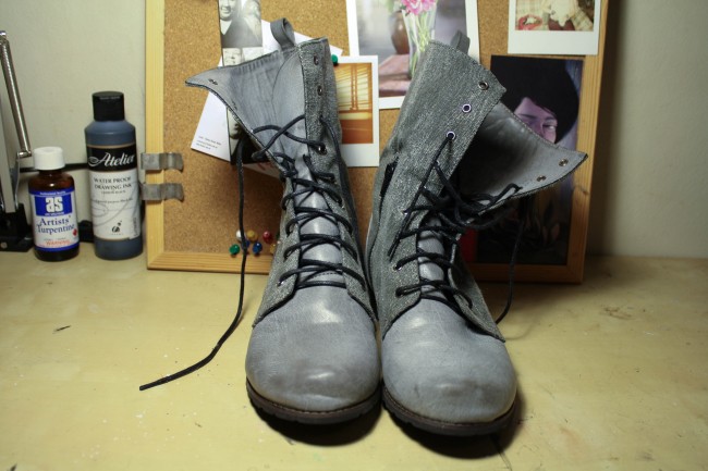 A pair of grey boots with black laces.