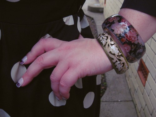 Close up shot of my hand on my hip, I'm wearing two big bangles and have pink nails with a darker pink bow tie on each nail.