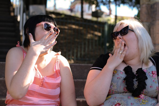 Sonya and Zoe posing with a hand to their mouths, feigning shock and horror.