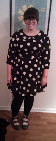 Photo of a chubby pale skinned woman with a blunt fringe and a broad smile wearing the polka dot dress.