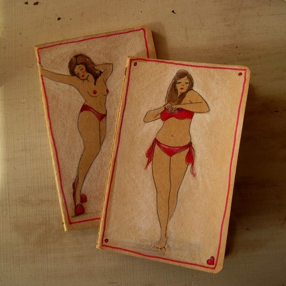 Photo of two brown covered Moleskin cahier notebooks with drawings of pin up girls on each cover.