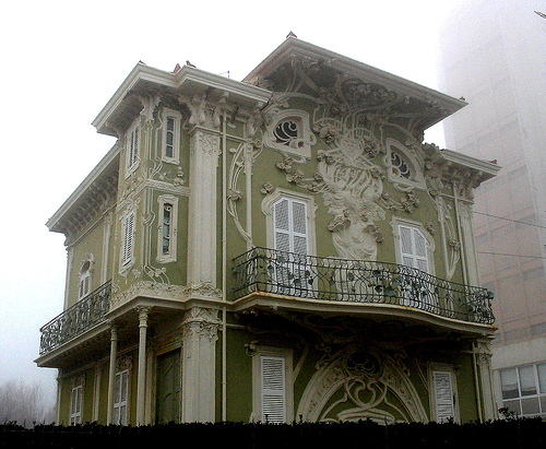 Photo of a very ornately decorated house painted apple green with white decorative details that look like distinctly Art Nouveau.