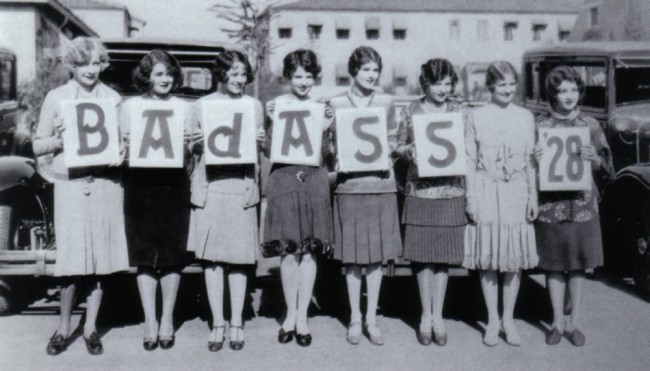 A black and white photo presumably from 1928 of eight women holding up letters that spell "BAdASS '28".