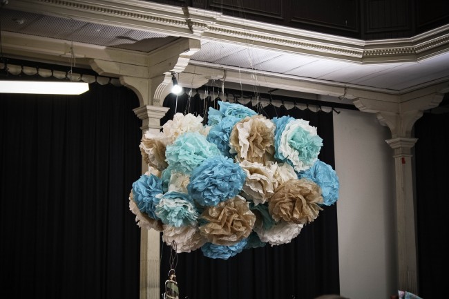 Photo of large blue, fawn and cream coloured pom poms hanging in a huge bunch from the ceiling of a large room