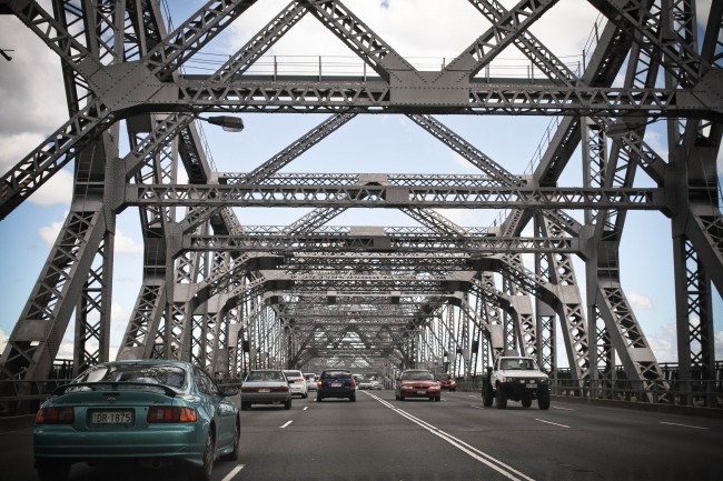 Photo of the Story Bridge while driving over it, the grey steel structure like huge mechano scaffolding arching over the six lane bridge.