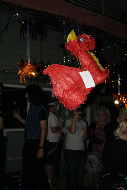 Photo of a red dragon shaped piñata with people looking on in the background.