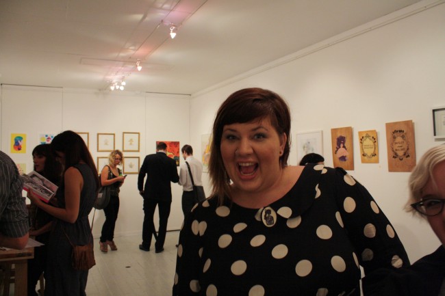 Photo of me making a "HIII" face inside a small gallery with white walls.