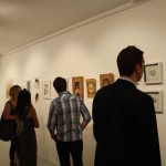 Photo of people looking at artworks on the wall.