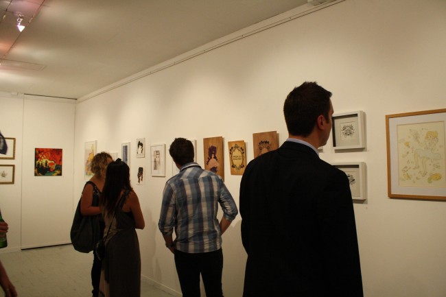 Photo of people looking at artworks on the wall.