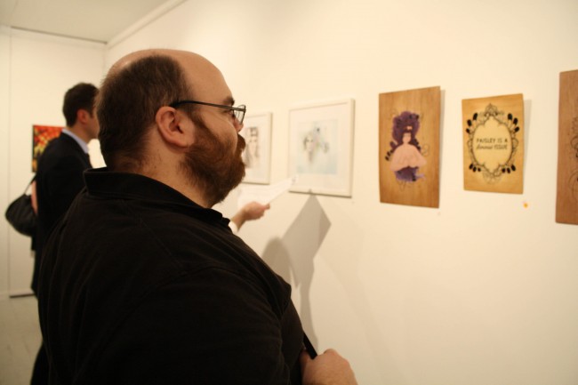 Photo of Nick staring at some artworks in a thoughtful manner. My work sits just to the left of his gaze.