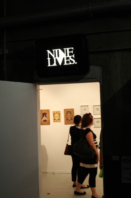 Photo of a sign saying "NINE LIVES" over a doorway which you can see through to an art gallery where some of my works are hanging.