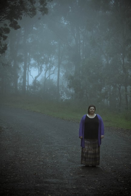 Photo of me standing on a road with very heavy fog almost obscuring the bush lined road behind me.