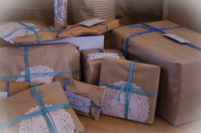 Photo of lots of brown paper wrapped presents with blue and green wool wrapped around them like ribbon.