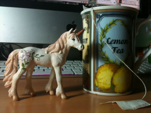 Photo of a small toy unicorn with a tea cup (that says Lemon Tea on the side).