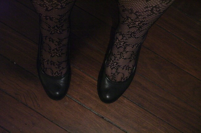 Photo of my ankles clad in lace fishnet tights and feet in black court shoes.