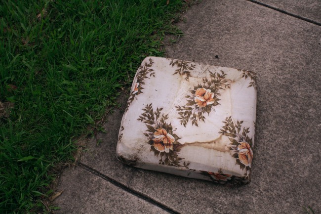 Photo of a floral covered seat cushion sitting on the footpath.