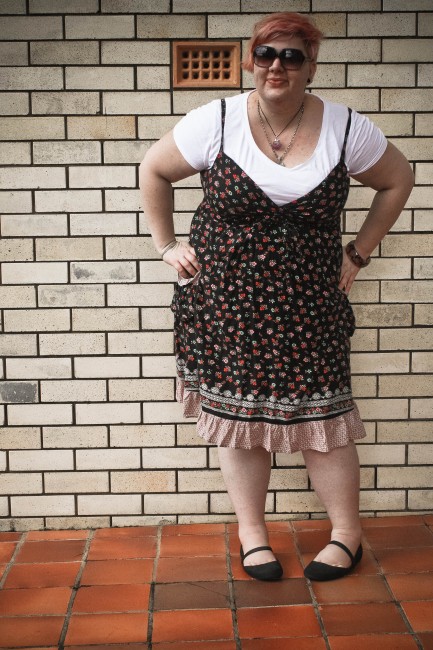 Outfit photo of me wearing the sundress and tshirt; my hands are on my hips and I'm bending over a bit oddly.