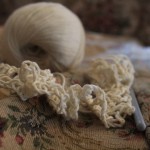 A photo of some cream yarn and crocheting on a floral tapestry couch.