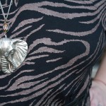 A close up photo of my huge metal elephant head necklace against my animal print dress.