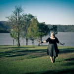 A photo of me standing with my arms reaching out daintily in front of a big dam.