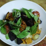 A photo of dinner: roast beetroot, pumpkin, garlic and cherry tomatoes on couscous served with balsamic vinegar reduction and many basil leaves.