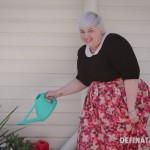 A photo of me holding a bright green watering can and pretending to water flowers.