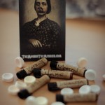 A photo of the sample vials scattered with the sherbert lollies and a The Morbid The Merrier business card standing behind.