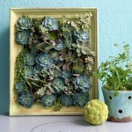 Image - a pale green frame with a tiny vertical garden of succulents planted inside it.