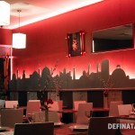 A photo of a pink wall in Little Malaya with a cityscape cut out of wood and lighting behind it.